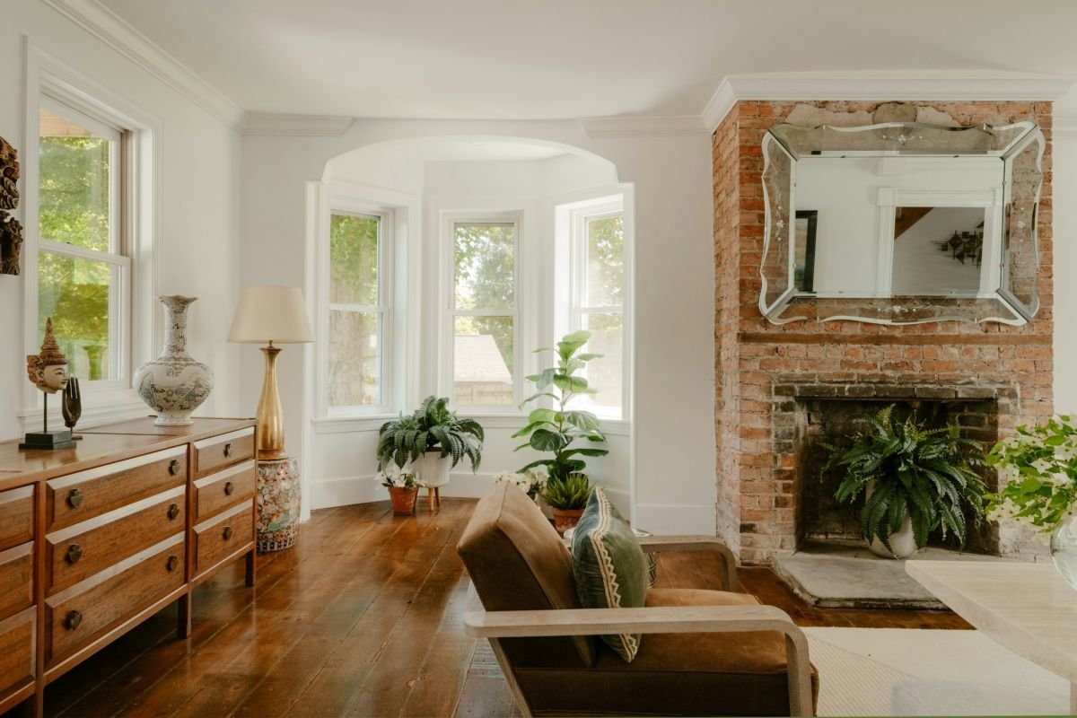 Sitting room with a bay window, brick fireplace and pale painted walls