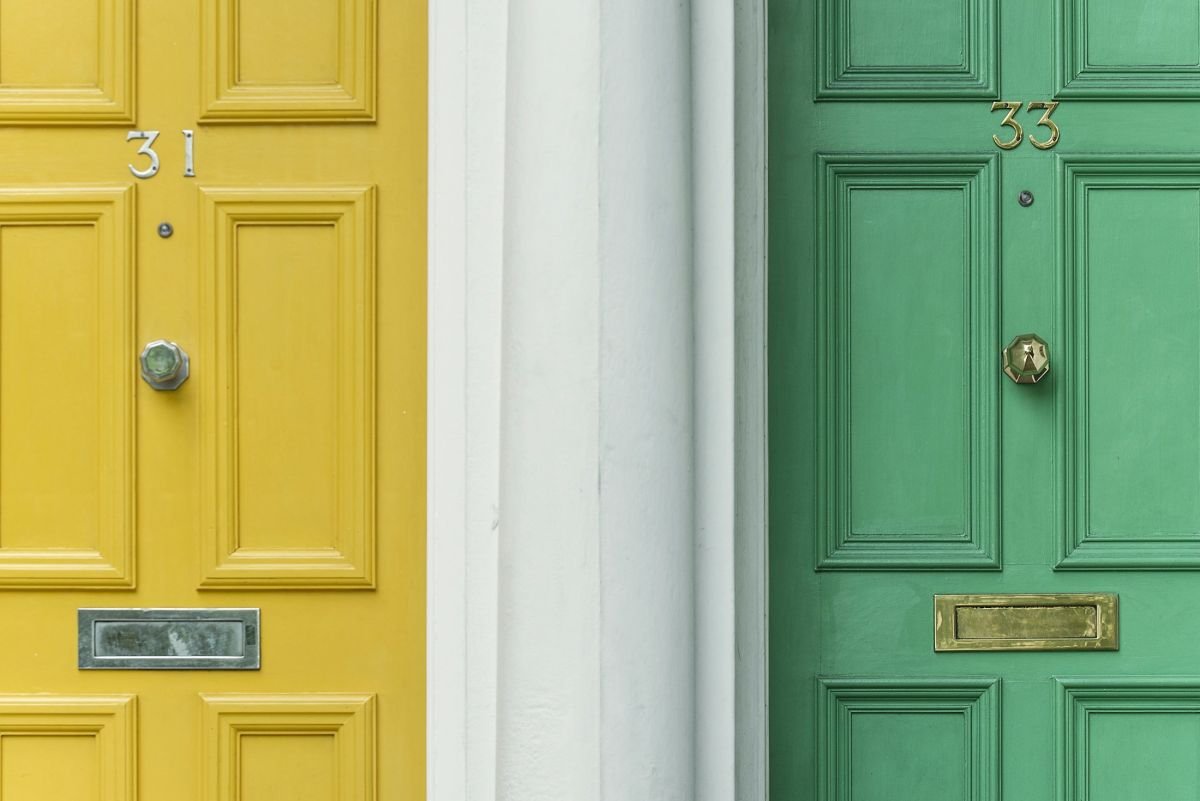 Two painted front doors side by side, mustard yellow and sage green