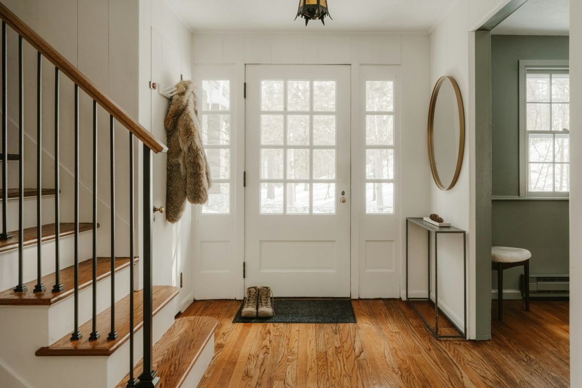 Entrance hall with a painted staircase, white front door and wooden floor