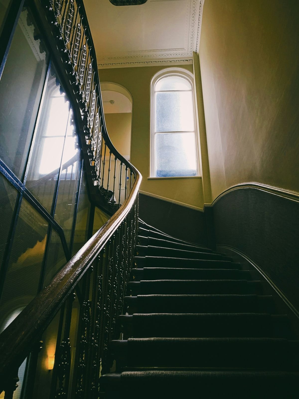 Dark green painted period stairwell with an arched window