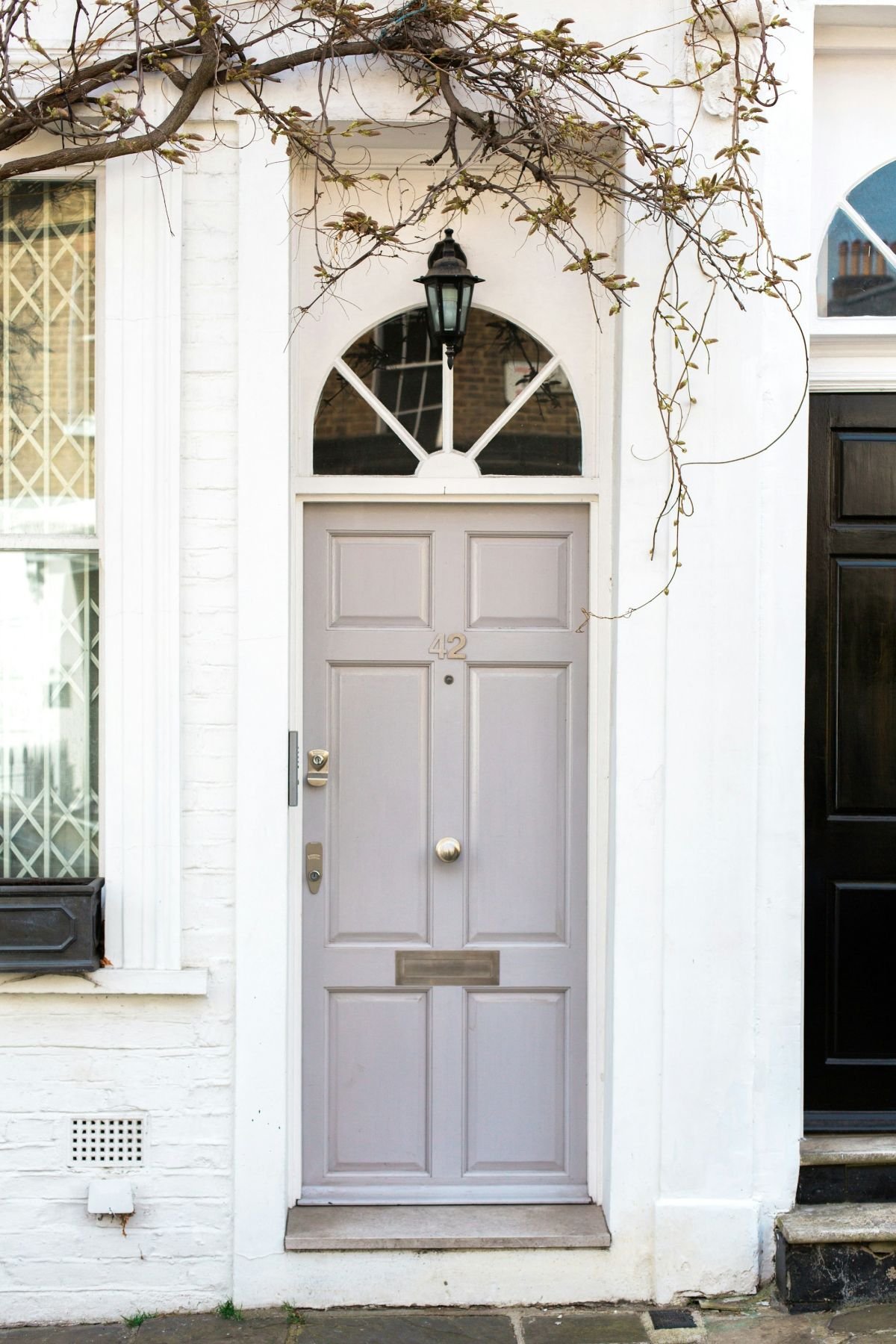 Pale grey painted panelled front door with a brass knob