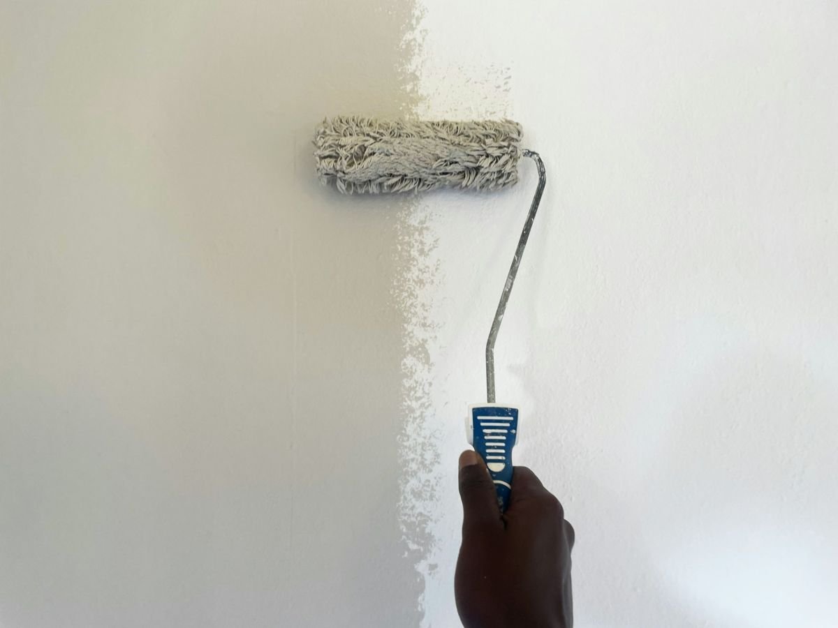 Roller applying a fresh coat of white paint to a wall