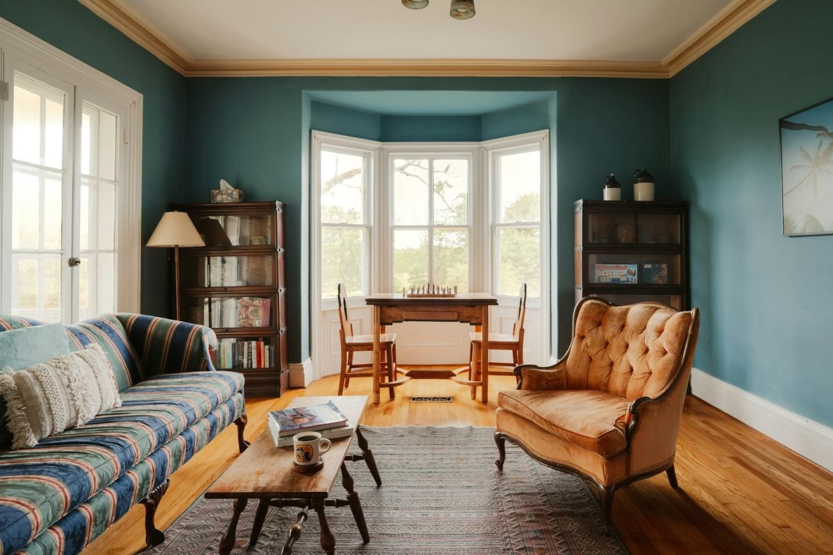 Deep teal painted room with a bay window and crisp white woodwork