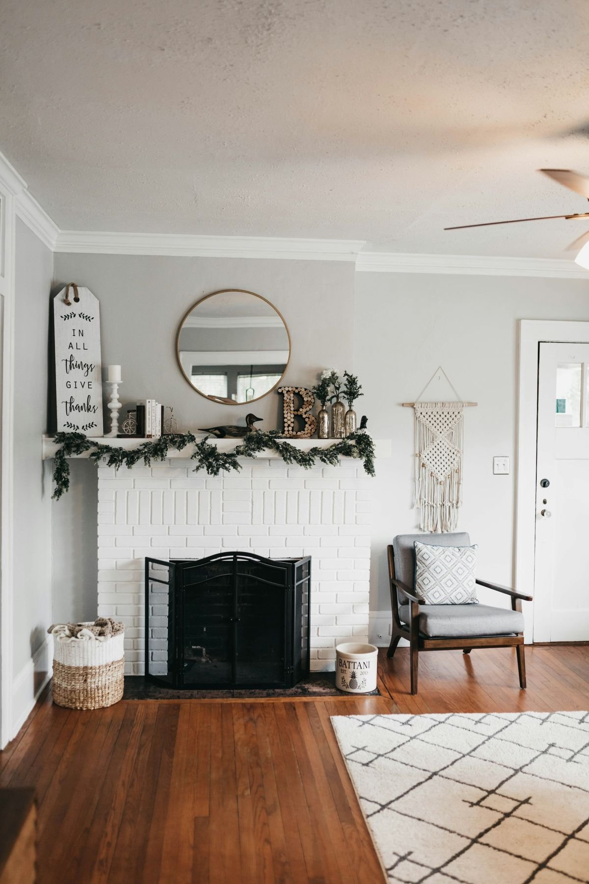 Calm white room with a painted fireplace surround and round mirror