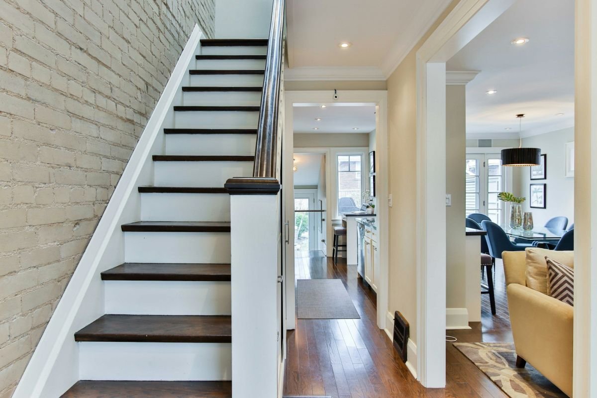 White painted staircase with dark treads against a painted brick wall